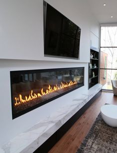 a living room with a fire place in the center and a television on the wall