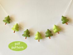 green felt christmas trees hanging from clothes pins on a string with the word pattern below