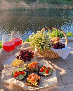 two baskets filled with food sitting on top of a picnic table next to a river