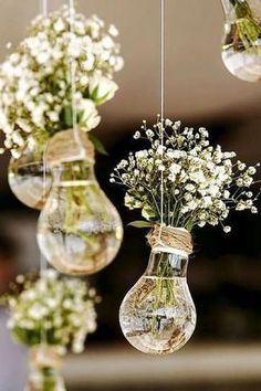 three hanging vases filled with white flowers and greenery are suspended from the ceiling