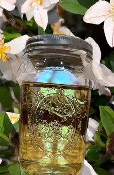 a mason jar filled with liquid surrounded by flowers