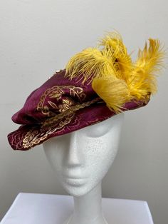 New women's Renaissance Medieval Elizabethan Victorian burgundy brocade brim hat cap. This stunning brim hat is embellished with a gold ostrich feather cluster secured with a gold broach. Under brim and lining is a matching fabric. Brim is 1 1/2" wide secured by a gold braid. Great for your next theme party, stage production or Renaissance Faire. Sales final. New not worn. Fitted High Crown Hat For Costumes, Curved Brim Mini Hats For Costumes, Costume Mini Wide Brim Hats Fitted, High Crown Fitted Hat For Costume, Fantasy High Crown Costume Hat, Fitted Cap Style Mini Hat For Costumes, Traditional Costume Hats And Headpieces For Carnival, Adjustable Ceremonial Costume Hat With Curved Brim, Adjustable Curved Brim Costume Hats For Carnival