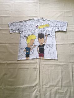 "1990s Beavis and Butt-Head t-shirt 1993 MTV Networks, Stanley De Santis all over print 100% pre-shrunk cotton, single stitch made in USA white w/all over print of Beavis and Butthead at concert rocking out good vintage condition, light stains, inc. collar (see photos) labeled XL, see below measures, lying flat, shoulder-21\" chest-22 1/2\" sleeve-9 1/2\" length-29\"" 90s Style Printed T-shirt For Streetwear, Band Merch All Over Print T-shirt For Streetwear, Band Merch T-shirt With All Over Print For Streetwear, Vintage All Over Print T-shirt For Streetwear, Vintage All-over Print T-shirt For Streetwear, Vintage All Over Print Streetwear Tops, Vintage All Over Print Tops For Streetwear, Vintage All-over Print Tops For Streetwear, 90s Short Sleeve Tops With All Over Print