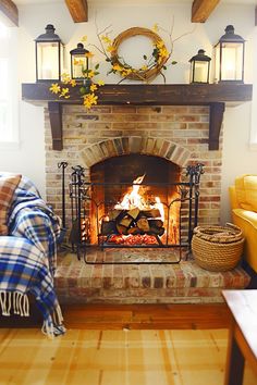 Rustic living room with a brick fireplace, wooden mantel, and decorative lanterns. Logs By Fireplace Decor, Rustic Fireplace Ideas, Cozy Brick Fireplace, Cottage Weekend, Wood Burners, Winter Pillow Covers, Log Storage, Decorative Lanterns