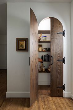 an open door leading to a pantry in a room with wood floors and white walls