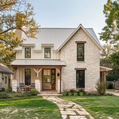 a white brick house sitting on top of a lush green field