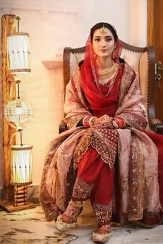 a woman sitting in a chair wearing a red and gold outfit