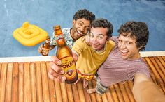 three men are posing for a photo while holding up two beer bottles and an inflatable object