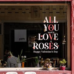 a window with the words all you need is love and roses written in pink on it