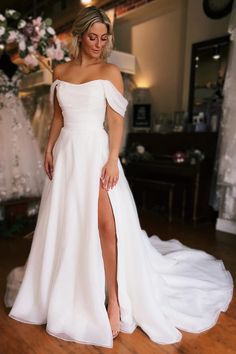 a woman in a white wedding dress standing on a wooden floor with her leg up