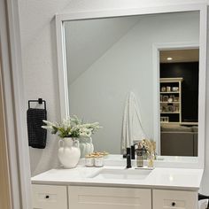 a bathroom vanity with a large mirror and vases on the counter top next to it