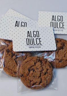 three chocolate chip cookies wrapped in cellophane on top of each other with the words algo dulce printed on them