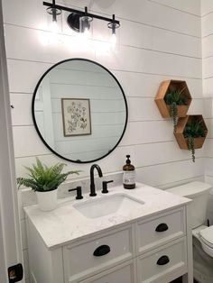 a bathroom with a sink, mirror and potted plant on the counter in front of it