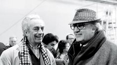 black and white photograph of two men wearing scarves, one smiling at the camera