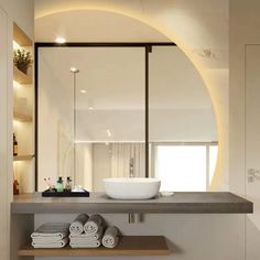 a bathroom with a sink, mirror and towels on the shelf in front of it