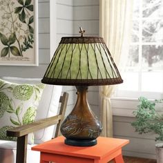 a lamp sitting on top of an orange table next to a white chair and window