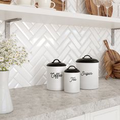 three white canisters sitting on top of a kitchen counter