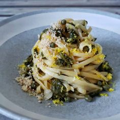 a white plate topped with pasta covered in broccoli and other toppings on top of it