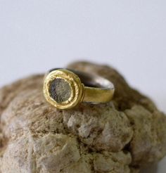 "A circular piece of ancient roman glass is set in a 24k gold bezel on a wide sterling silver band. This ancient roman glass silver and gold ring would make a unique engagement ring or wedding band, or a great everyday ring. The wide 5mm silver band has a comfort fit profile (oval on the inside and round on the outside), making it very comfortable. The band itself is wrapped in 24k gold giving it the appearance of a gold ring. On both sides of the ring is a 22k gold wire, adding a small yet love Silver And Gold Ring, Roman Glass Jewelry, Ancient Roman Glass, Persian Turquoise, Everyday Ring, Handmade Fine Jewelry, Glass Ring, Unique Engagement Ring, Ringe Gold