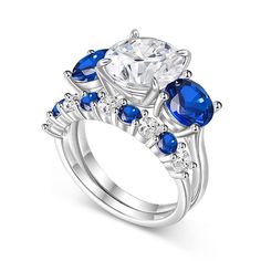 a white gold ring with blue and clear stones on the sides, surrounded by diamonds