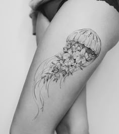 a black and white photo of a woman's thigh with flowers on her leg