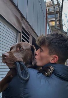 a man is holding a dog in his arms and kissing it's face on the door