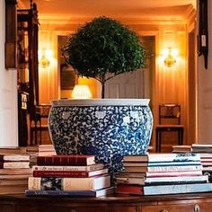 a blue and white vase sitting on top of a table filled with books