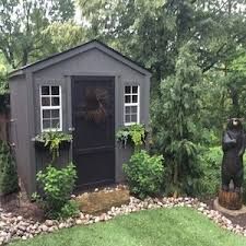 a garden shed with two statues in the yard