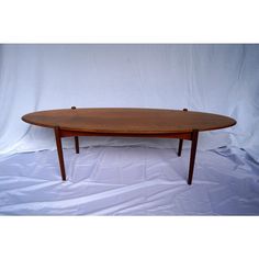 an oval wooden table sitting on top of a white sheet