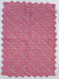 a pink crocheted dishcloth on a white cloth with holes in the middle