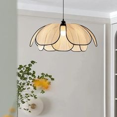 a light fixture hanging from the ceiling in a room with white walls and yellow flowers