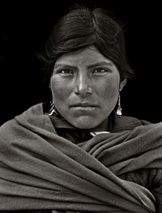 an old black and white photo of a woman wearing a shawl over her head