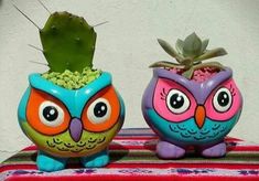 two ceramic owls sitting next to each other on a table with a cactus in the middle