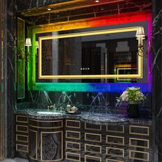 a bathroom with marble counter tops and rainbow colored mirror