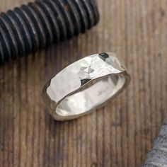 a silver ring sitting on top of a wooden table next to a black and white object