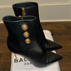 Balmain "Roni" Smooth Calfskin Leather Booties. 4" Metallic Stiletto Heel. Pointed Cap Toe. Golden Logo Button Detailing. Side Zip Eases Dress. Calfskin Leather Lining. Smooth Sole. Made In Italy. New Dustbag Only No Box Designer Heels With Gold-tone Hardware And Pointed Toe, Luxury Ankle Boots With 4-inch Heel, Designer Party Heels With Gold-tone Hardware, Luxury High Heels With Gold-tone Hardware, Luxury Party Boots, Luxury Gold Leather Heeled Boots, Luxury Party Boots With Reinforced Heel, Luxury High Heel Boots For Formal Occasions, Designer Calf Leather Heels With Gold-tone Hardware