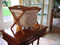 a wooden table topped with a basket on top of it's side shelf next to a glass case