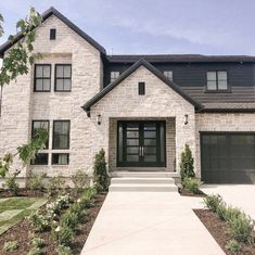 a large white brick house with two garages and black doors on the front door