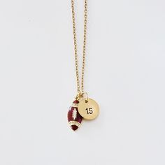 a gold plated necklace with a football ball and number 15 on it, sitting on a white surface