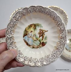 a hand holding an ornately decorated porcelain bowl