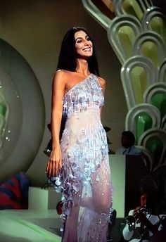 a woman is walking on the runway in a dress with sequins and beads