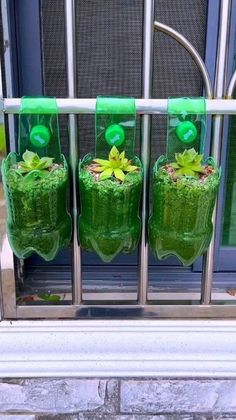 three green vases with plants in them on a window sill