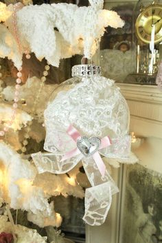 an ornament hanging from the tree in front of a white christmas tree with pink ribbon