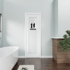 a bathroom with a white bath tub sitting next to a wooden cabinet and plant on the floor