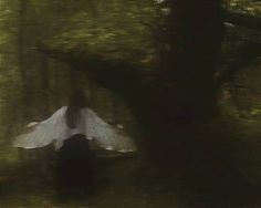 a blurry image of a woman in the woods with her arms spread wide open