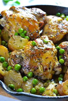 chicken and potatoes in a skillet with peas on the side, ready to be eaten