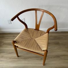 a wooden chair sitting on top of a hard wood floor next to a white wall