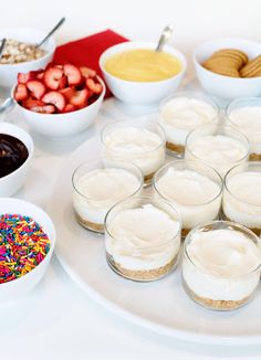 desserts and condiments are arranged on a white platter with colorful sprinkles