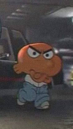 an orange bird with big eyes standing in the middle of a parking lot next to parked cars