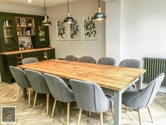 a wooden table surrounded by grey chairs in a room